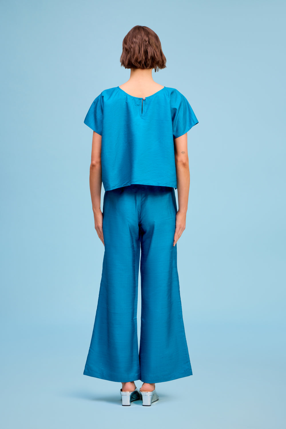 Model wearing Livro Paloma Pant in teal, back view.
